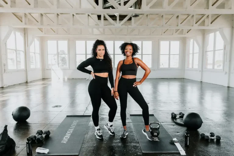 Two fit women at the gym ready to lift weights.